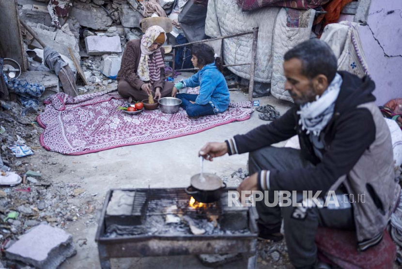 Anggota keluarga Al-Rabaya berbuka puasa selama bulan suci Ramadhan di luar rumah mereka yang hancur akibat serangan udara Israel di Rafah, Jalur Gaza, Senin, (18/3/2024).