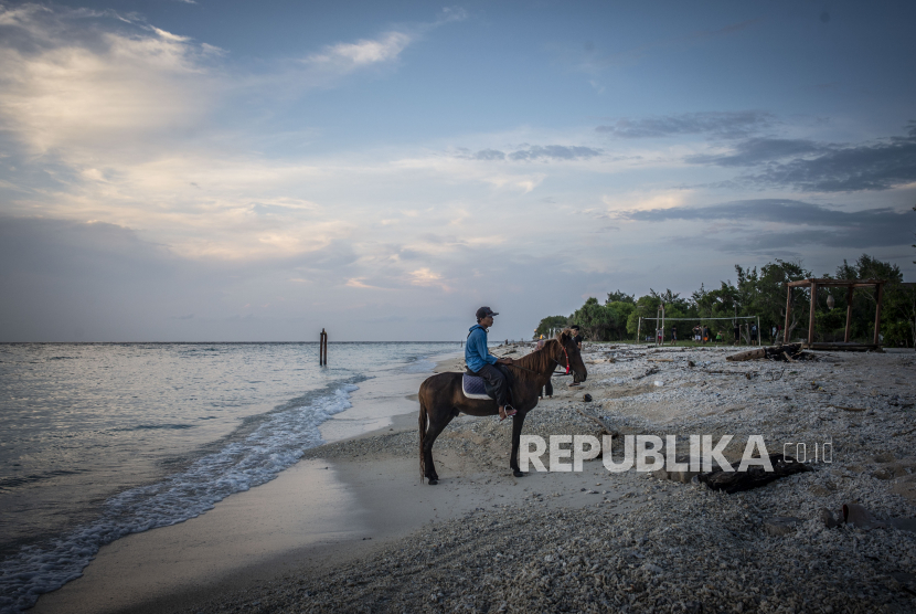 Seorang penyedia jasa kuda menaiki kudanya saat menanti kunjungan wisatawan di Gili Trawangan, Kepulauan Gili, Lombok Utara, Nusa Tenggara Barat. Pemkab Lombok Utara menerapkan sistem satu pintu untuk ke kawasan wisata tiga gili.