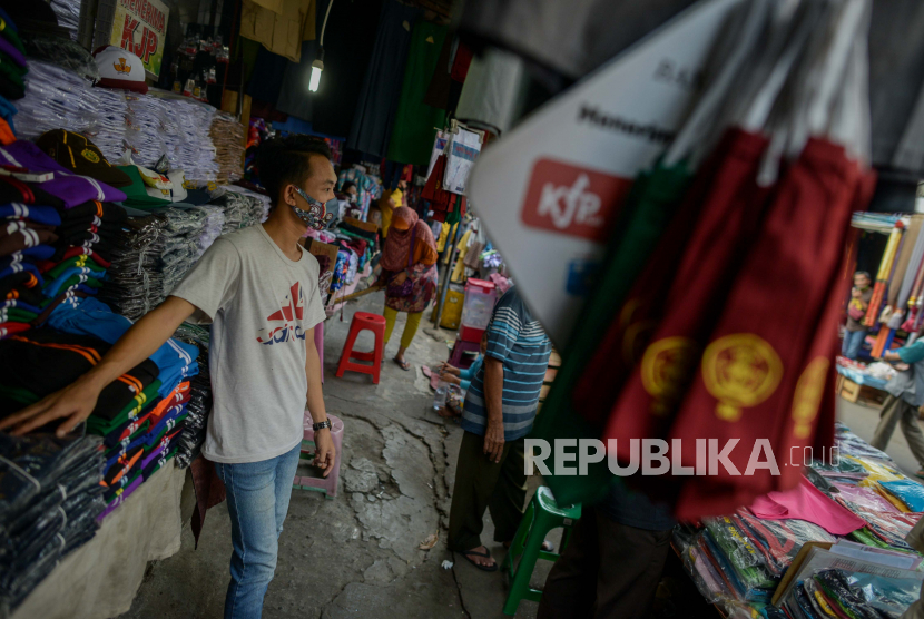 Pedagang mengenakan masker menunggu pembeli di Pasar Jatinegara, Jakarta, Selasa (30/6).  