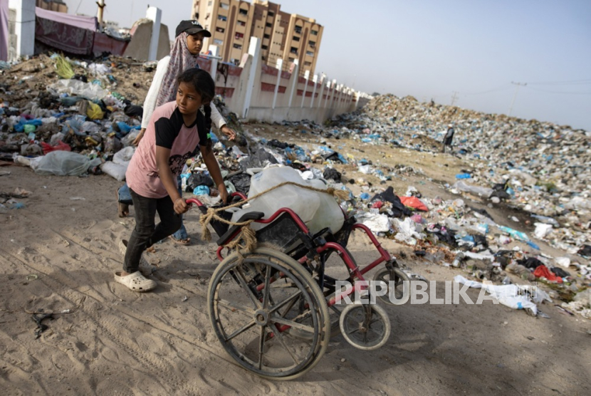 Anak-anak pengungsi Palestina berjalan melewati tumpukan sampah di dekat Khan Yunis, Jalur Gaza selatan, 18 Mei 2024. 