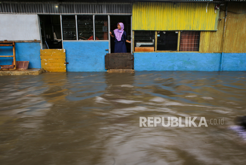 Warga mengamati banjir di depan kios miliknya di kawasan Manis, Jatiuwung, Kota Tangerang, Banten, Ahad (22/11/2020).