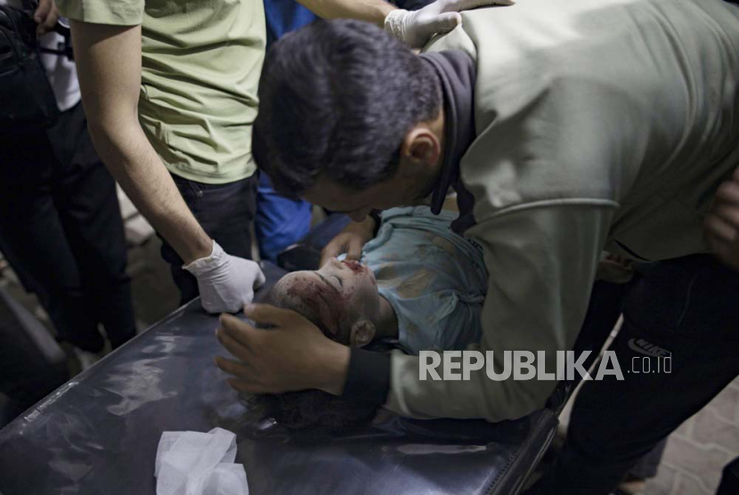 Seorang ayah yang memegang jenazah putrinya yang terbunuh dihibur di Rumah Sakit Kuwait setelah serangan udara Israel menghantam rumah mereka di kamp pengungsi Rafah, Jalur Gaza selatan, 19 April 2024