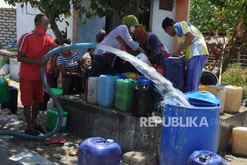 Warga mengisi air ke dalam penampungan saat pendistribusian air bersih. 