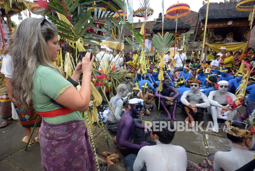 Wisatawan memotret warga yang berhias warna-warni saat tradisi Ngerebeg di Desa Tegallalang, Gianyar, Bali, Rabu (13/7/2022). 