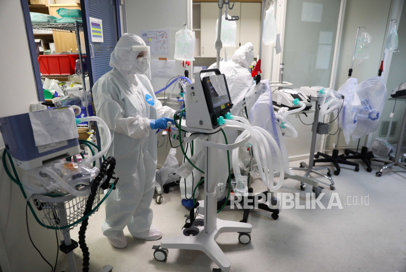 Seorang petugas medis yang mengenakan pakaian pelindung lengkap membawa ventilator untuk pasien.