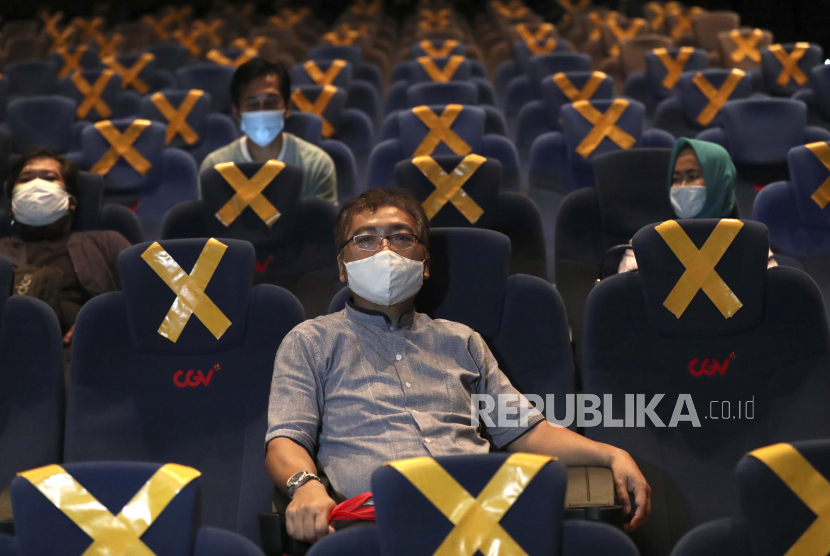  Orang-orang duduk terpisah di tengah penanda jarak fisik saat mereka menunggu dimulainya film di bioskop CGV Cinemas di Jakarta, Indonesia, Jumat, 23 Oktober 2020. Bioskop tersebut dibuka kembali minggu ini setelah ditutup berbulan-bulan karena wabah virus corona.
