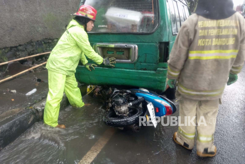 Satu unit sepeda motor terbawa arus air saat hujan deras terjadi di Jalan Dr Setiabudi, Kota Bandung, Selasa (27/2/2024) sore. Sepeda motor tersangkut di kolong mobil. 