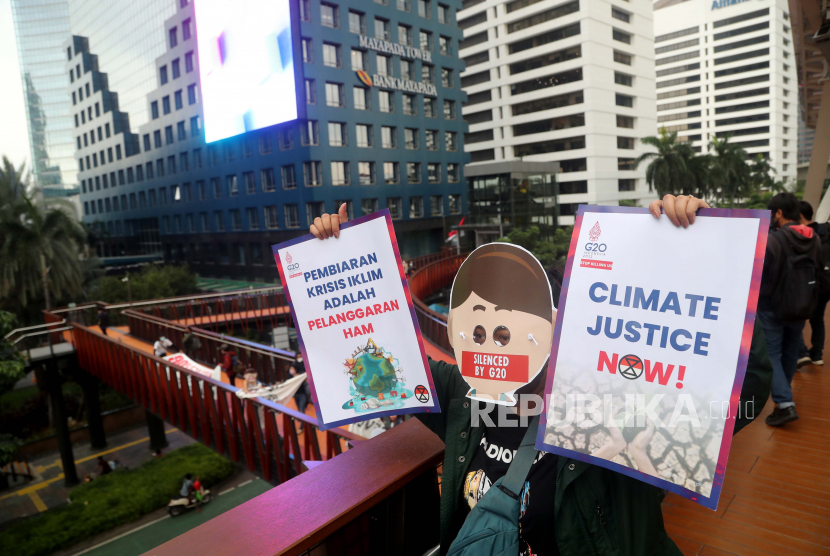 Aktivis Indonesia memegang spanduk mereka di jembatan penyeberangan saat protes di Jakarta, Indonesia, 14 November 2022. Puluhan aktivis dari Extinction Rebellion Indonesia (XR Indonesia) dan Walhi Jakarta melakukan aksi yang menggambarkan sikap diam para aktivis selama acara G20 di Bali dan menyerukan para pemimpin untuk menghentikan praktik ekonomi 