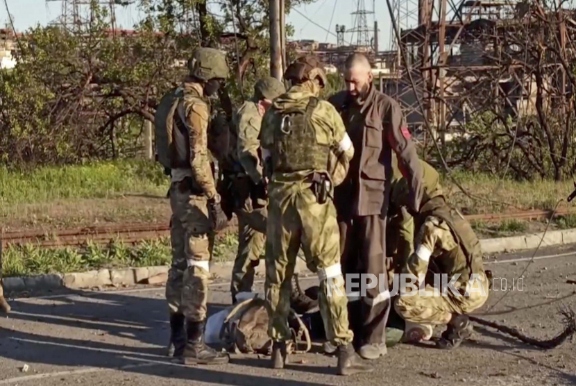 Gambar diam selebaran yang diambil dari video selebaran yang disediakan oleh layanan pers Kementerian Pertahanan Rusia menunjukkan prajurit Rusia menggeledah prajurit Ukraina saat mereka dievakuasi dari pabrik baja Azovstal yang terkepung di Mariupol, Ukraina, 17 Mei 2022. Perundingan damai antara Rusia dan Ukraina masih mengalami kebuntuan.  