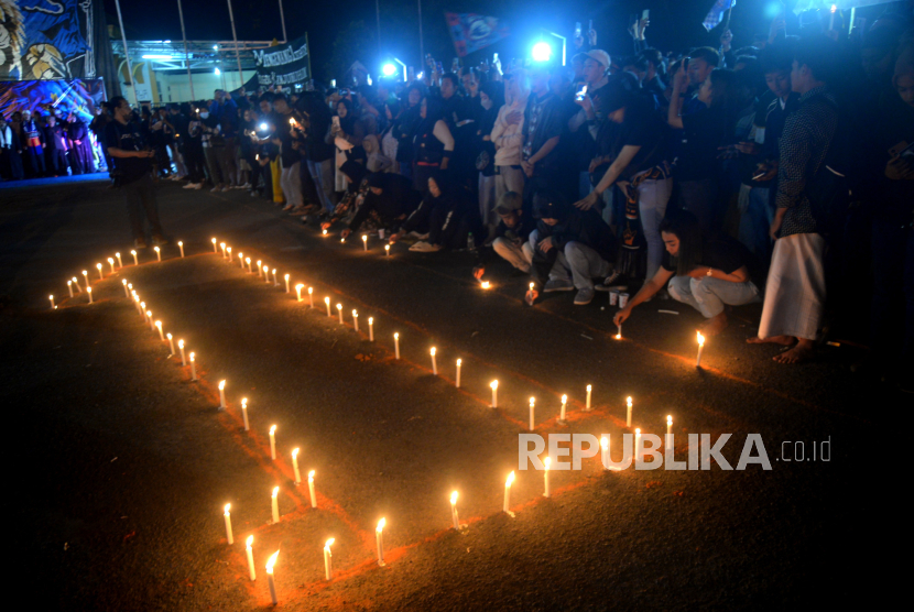 Aremania menyalakan lilin saat malam peringatan setahun Tragedi Kanjuruhan di Stadion Kanjuruhan, Malang, Ahad (1/10/2023). Komnas HAM sebut kejadian di pintu 13 belum juga terungkap.