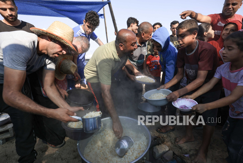 Orang-orang membagikan makanan di kamp darurat bagi para pengungsi di Khan Yunis di Jalur Gaza selatan pada Rabu (25/10/2023.