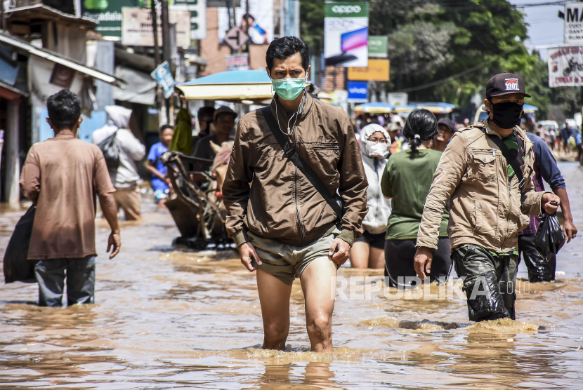 Sejumlah warga melintasi genangan air saat banjir di ruas Jalan Raya Dayeuhkolot, Kabupaten Bandung, Rabu (1/4). Sedikitnya 60 ribu jiwa dan 10 ribu rumah dari tujuh kecamatan di Kabupaten Bandung tersebut terdampak banjir akibat luapan sungai Citarum serta intensitas curah hujan yang tinggi