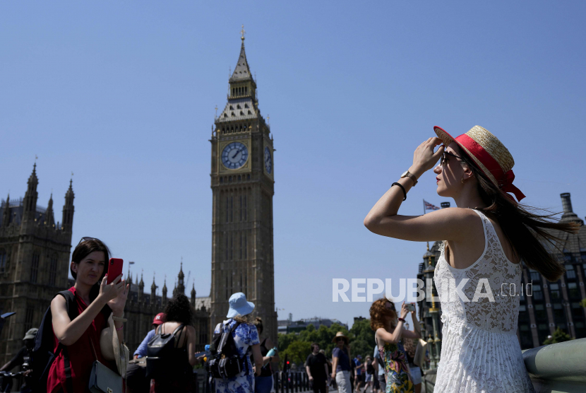 Turis berpose untuk foto di Westminster Bridge di London, Selasa, 19 Juli 2022. Jutaan orang di Inggris terbangun dari malam terpanas di negara itu pada Selasa dan bersiap menghadapi hari ketika suhu bisa memecahkan rekor, saat gelombang panas yang menghanguskan Eropa melanda sebuah negara yang tidak dibangun untuk ekstrem seperti itu. Gelombang Panas, Petugas Pemadam Kebakaran London Siaga