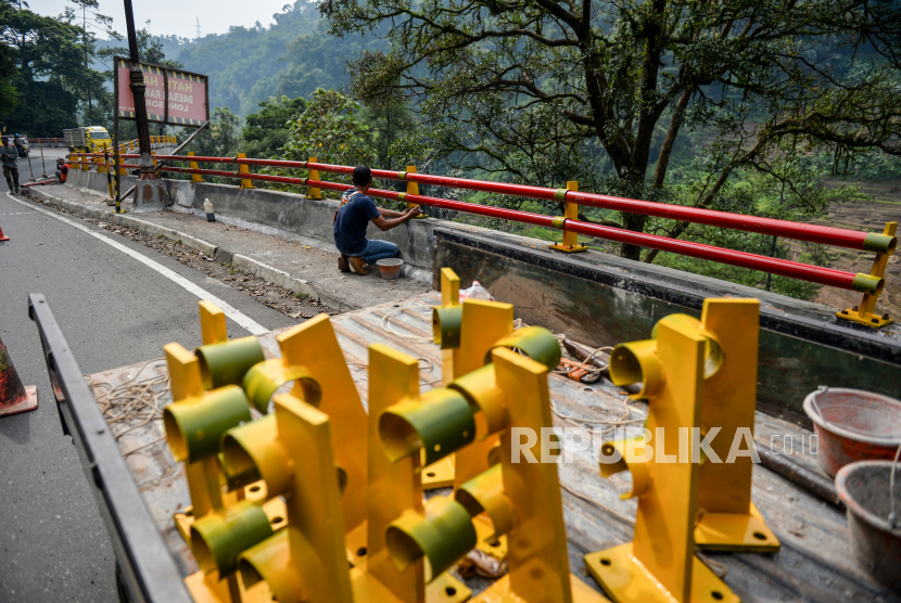 Pekerja memasang pembatas jalan di Jalur Cadas Pangerang, Kabupaten Sumedang, Jawa Barat, Jumat (7/4/2023). 