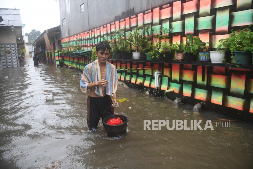 Warga berjalan melintasi banjir yang merendam kawasan RW 5, Duren Tiga, Pancoran, Jakarta, Kamis (18/2/2021). Sejumlah kawasan di Jakarta terendam banjir akibat curah hujan yang tinggi. 