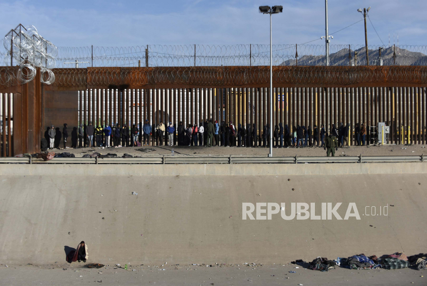 Migran berbaris di samping Rio Bravo (Rio Grande) terlihat dari Ciudad Juarez, Meksiko, 23 Desember 2022, di perbatasan antara Meksiko dan AS.