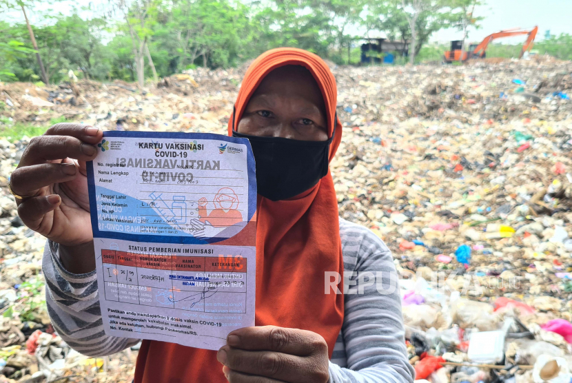 Seorang pengepul sampah menunjukkan surat vaksin usai disuntik Vaksin COVID-19 pada pelaksanaan vaksinasi untuk komunitas pemulung dan pengepul sampah di Tempat Pembuangan Akhir (TPA) Sampah Rawa Kucing, Tangerang, Banten, Selasa (28/9/2021). Vaksinasi yang diselenggarakan oleh Pemkot Tangerang yang bekerjasama dengan Danone Indonesia bertujuan untuk meningkatkan herd imunity atau kekebalan kelompok bagi pemulung dan pengepul sampah. 
