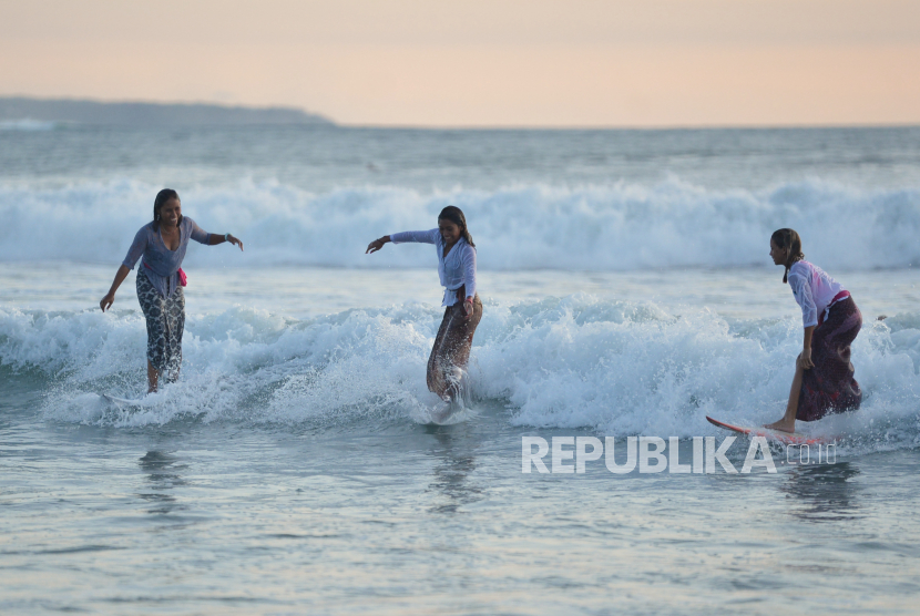 Atraksi selancar perempuan berbusana kebaya di Pantai Kuta, Badung, Bali, Ahad (16/4/2023). Turis bisa latihan selancar di Pantai Kuta.
