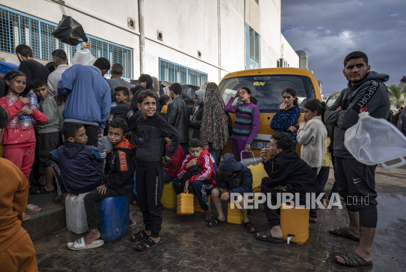 Warga Palestina yang mengungsi akibat pemboman Israel di Jalur Gaza mengantri untuk mendapatkan air di kamp pengungsian PBB di kota selatan Khan Younis, Jalur Gaza, Ahad, (19/11/2023).
