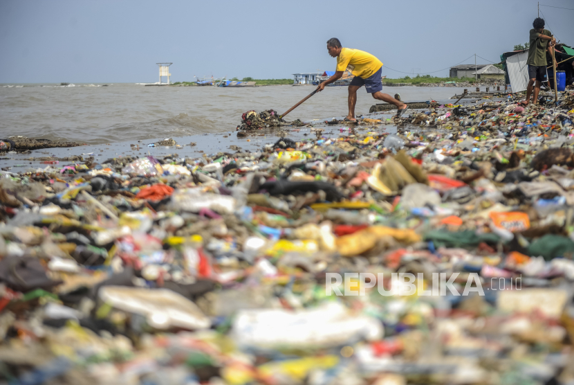 Warga membersihkan sampah yang terbawa gelomb Gelombang tinggi yang terjadi di perairan Selat Sunda sejak sepekan terakhir 
