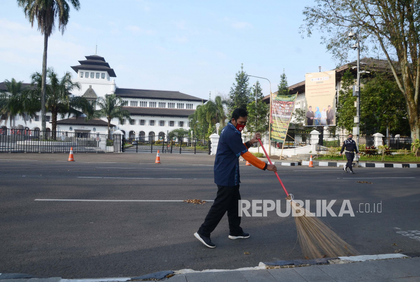 Petugas kebersihan menyapu jalan depan Gedung Sate, Jalan Diponegoro, Kota Bandung. Gedung Sate ditutup karena karyawan yang positif Covid-19.