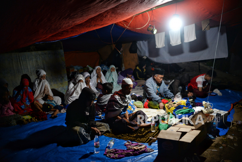 Sejumlah pengungsi memanjatkan doa usai melaksanakan shalat maghrib di Kampung Gasol II, Desa Gasol, Cugenang, Kabupaten Cianjur, Jawa Barat, Kamis (24/11/2022).Berdasarkan data dari BNPB, hingga hari Kamis (24/11/2022) jumlah pengungsi akibat gempa di Cianjur mencapai 62.545 orang. Republika/Thoudy Badai