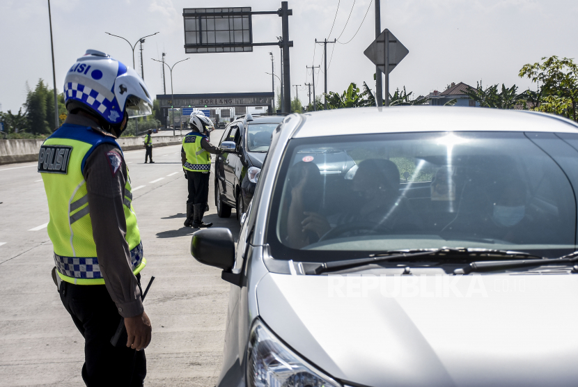 Petugas kepolisian memeriksa identitas dan surat keterangan sehat dari pengemudi kendaraan dengan pelat nomor luar Bandung saat operasi ppkm mikro di gerbang keluar Tol Soreang, Kabupaten Bandung, Ahad (20/6). Penyekatan dan pemeriksaan tersebut merupakan tindak lanjut dari status wilayah Bandung Raya siaga satu Covid-19 serta ditujukan untuk menekan mobilitas kendaraan agar tidak masuk ke wilayah Bandung Raya demi mencegah penyebaran Covid-19. Foto: Republika/Abdan Syakura