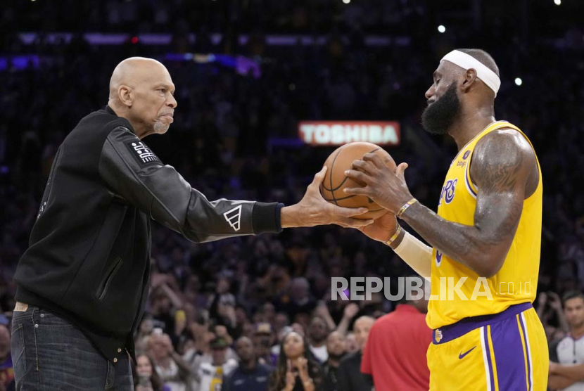 Kareem Abdul-Jabbar, left, hands the ball to Los Angeles Lakers forward LeBron James after passing Abdul-Jabbar to become the NBA all-time leading scorer during the second half of an NBA basketball game against the Oklahoma City Thunder Tuesday, Feb. 7, 2023, in Los Angeles.