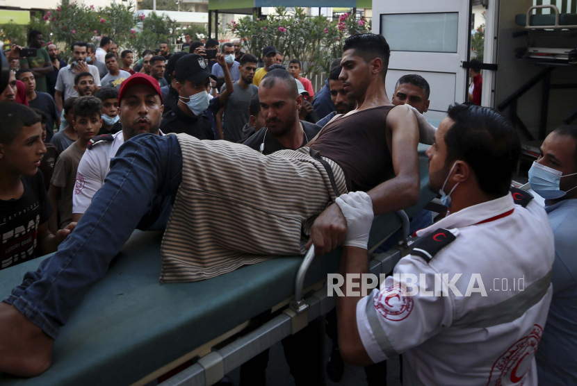 Petugas medis memindahkan seorang pemuda yang terluka, yang ditembak oleh pasukan Israel di kakinya saat protes di perbatasan Jalur Gaza dengan Israel, ke ruang perawatan rumah sakit Shifa di Kota Gaza, Sabtu, 21 Agustus 2021.