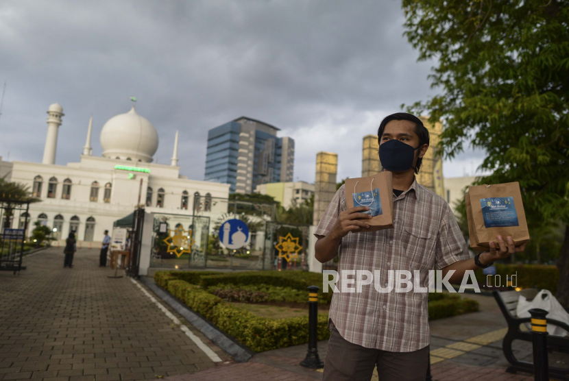 Petugas membagikan takjil dengan sistem drive thru di Masjid Agung Al-Azhar, Jakarta, Ahad (26/4). Selama Bulan Ramadan, pengurus Masjid Agung Al-Azhar membagikan sebanyak 300 takjil kepada pengendara yang melintas di sekitar lokasi tersebut