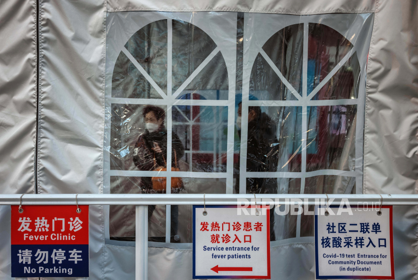 Orang-orang berdiri di klinik demam darurat di depan rumah sakit, di Shanghai, China, 23 Desember 2022. Rumah sakit di China kesulitan untuk mengatasi karena meningkatnya jumlah kasus COVID-19. 