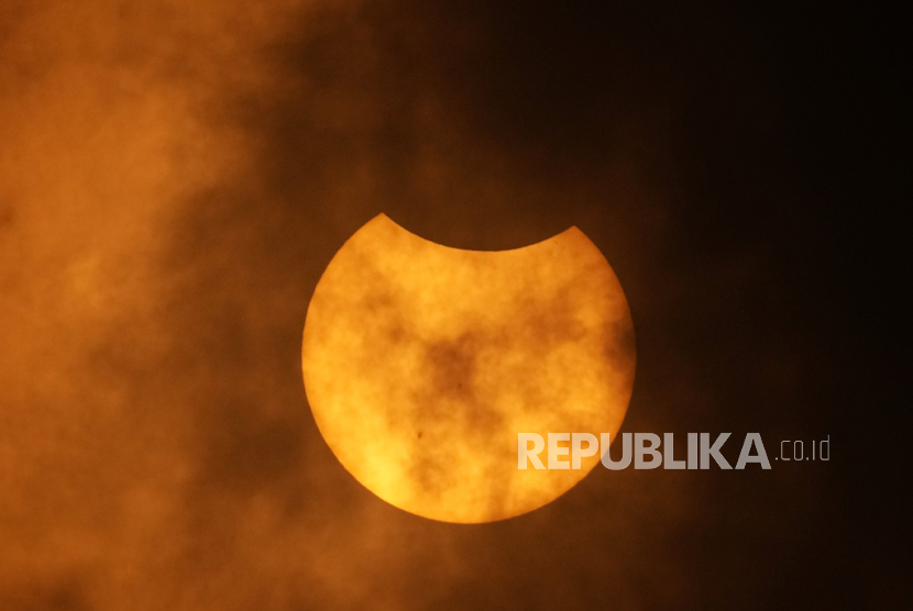 Bulan terlihat di balik awan saat mulai bergerak di depan Matahari saat terjadi gerhana matahari cincin. Bertepatan dengan fenomena itu, NASA meluncurkan 3 roket.