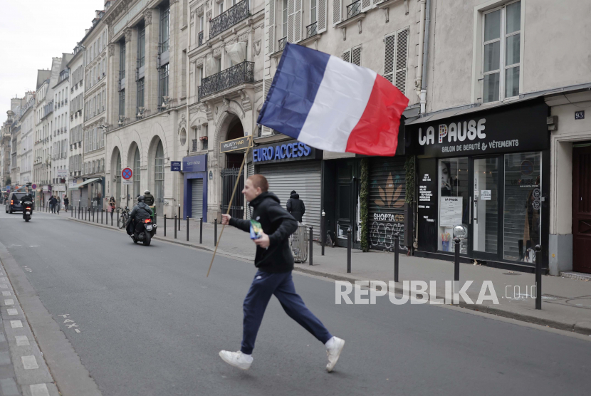 Seorang pria menyeberang jalan dengan bendera Prancis di tangannya. ilustrasi