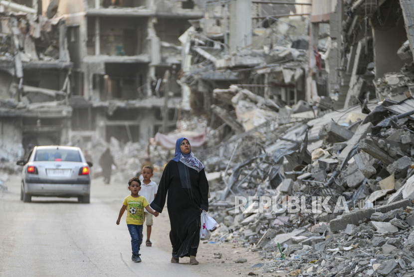 Warga Palestina berjalan di antara bangunan yang hancur akibat serangan udara dan darat Israel di Khan Younis, Jalur Gaza, Kamis, 12 September 2024.