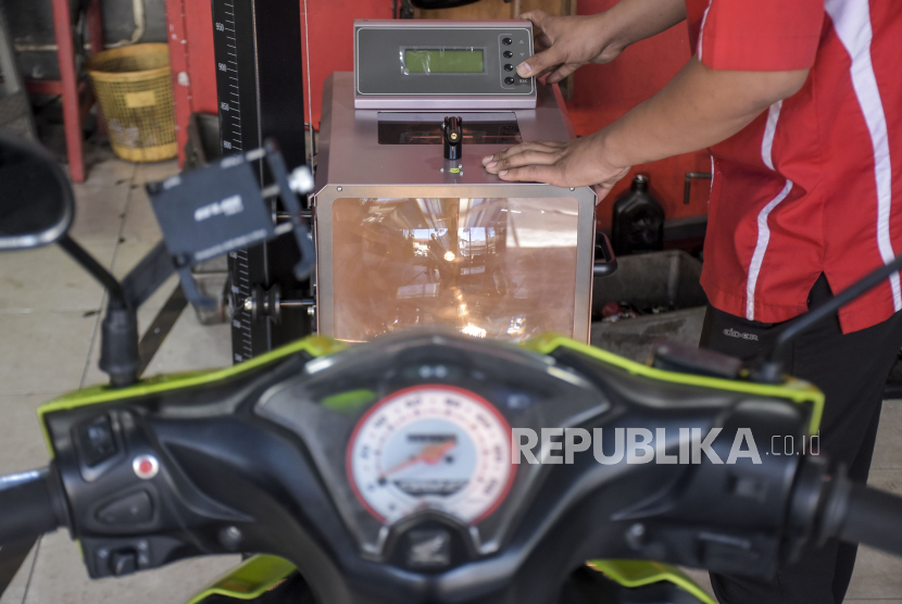 Teknisi mengukur intensitas cahaya sepeda motor bbm yang dikonversi menjadi sepeda motor listrik di bengkel Bacip Moto Shop, Jalan Kebon Jati, Kota Bandung, Jawa Barat, Senin (3/7/2023). 
