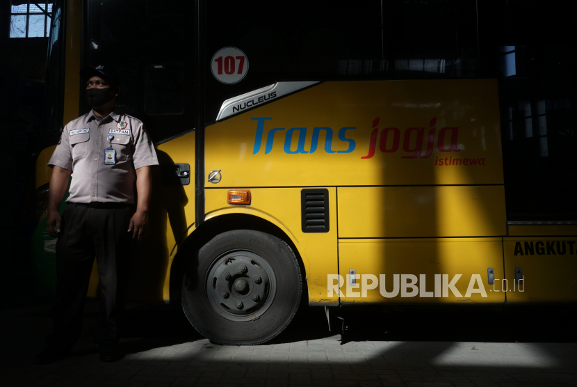 Petugas berdiri di dekat bus Trans Jogja yang terparkir  di garasi bus Trans Jogja, Gamping, Sleman, D.I Yogyakarta. Kemenhub sebut rute baru Trans Jogja bisa mengurangi kemacetan di spot tertentu.