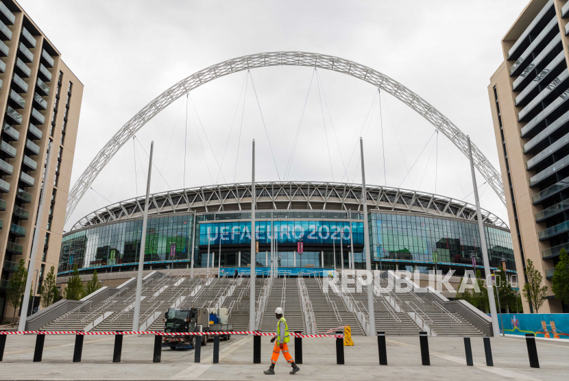 Seorang pekerja konstruksi berjalan di depan Stadion Wembley menjelang turnamen sepak bola UEFA EURO 2020 di London, Inggris, 11 Juni 2021.