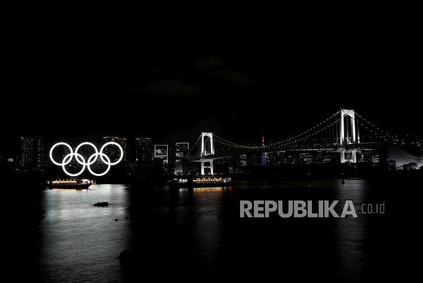 Perahu berlayar melewati cincin Olimpiade raksasa dan Jembatan Pelangi di area tepi laut Taman Laut Odaiba, Tokyo, Jepang, Jumat (2/4). Sejumlah landmark dari Jepang dihias dengan lampu-lampu yang menyala dalam rangka menyambut 100 hari sebelum dimulainya Olimpiade Tokyo 2020. REUTERS/Kim Kyung-Hoon     SEARCH 
