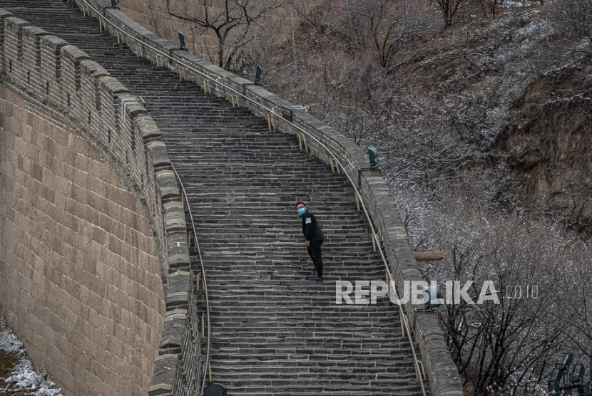 Seorang turis mengenakan masker berjalan di Tembok Besar Badaling yang hampir kosong, di Beijing, Cina, 26 Maret 2020. China melaporkan 45 kasus baru corona di China daratan pada 28 Maret. Jumlah ini turun dari 54 pada hari sebelumnya, yang hanya melibatkan pelancong dari luar negeri.