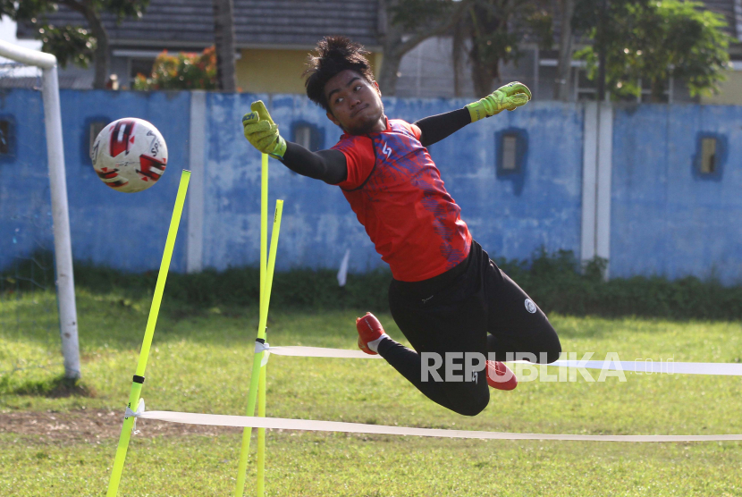 Penjaga gawang tim Arema FC, Kartika Aji berusaha menepis bola saat mengikuti latihan di lapangan Satsui Tubun, Malang, Jawa Timur, beberapa waktu lalu.