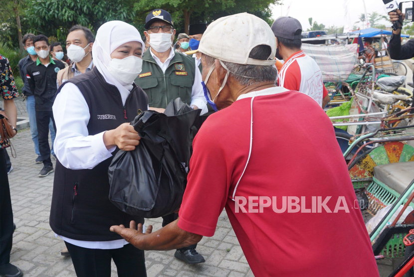 Gubernur Jawa Timur Khofifah Indar Parawansa (kiri) menyerahkan bantuan sembako kepada pengayuh becak di sela kegiatannya meninjau pelaksanaan vaksinasi Covid-19.