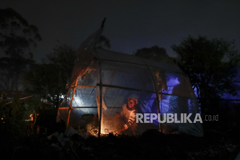 Seorang warga memasak di dalam tenda darurat saat meninggalkan rumahnya yang terkena dampak gempa bermagnitudo 5,6 di Cianjur, Indonesia, 25 November 2022. 