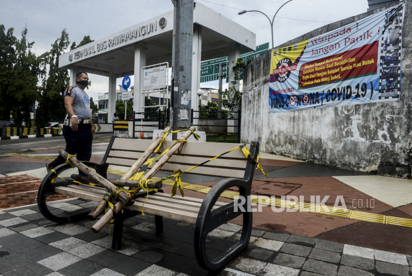 Petugas Dishub melintas di dekat bangku trotar yang disegel garis pembatas dan ditutupi bambu di kawasan Rawamangung, Jakarta, Senin (4/5). Bangku trotoar di sepanjang jalan Rawamangun disegel untuk mencegah kerumunan warga untuk mengantisipasi penyebaran virus Corona