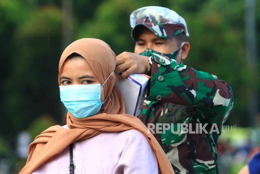 Seorang personel TNI AD memasangkan masker kepada warga yang terjaring razia kepatuhan penggunaan masker di Taman Digulis, Pontianak, Kalimantan Barat, Ahad (12/7/2020).