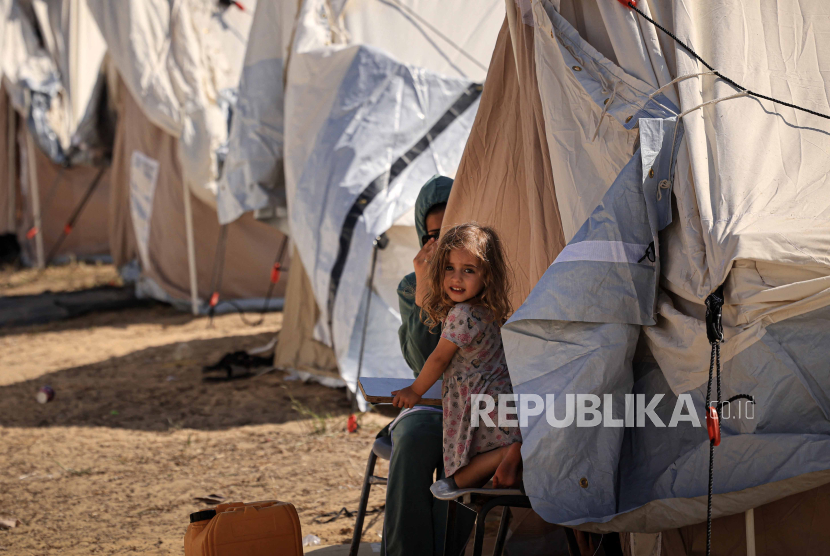 Anak kecil perempuan duduk di antara tenda-tenda yang didirikan untuk warga Palestina yang mencari perlindungan di halaman pusat Badan Bantuan dan Pekerjaan PBB untuk Pengungsi Palestina (UNRWA) di Khan Yunis di Jalur Gaza selatan pada Kamis (19/10/2023).