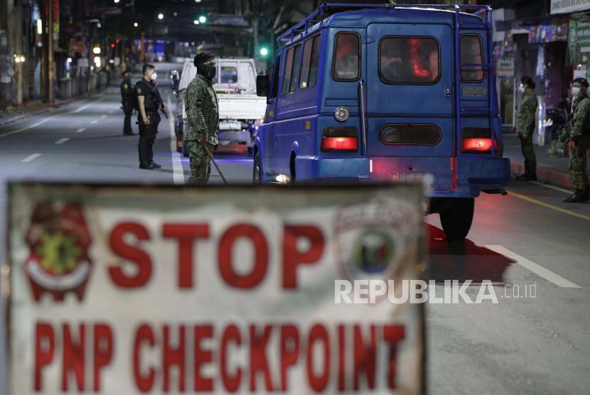 Polisi memeriksa kendaraan di pos pemeriksaan karena jam malam diberlakukan untuk mencegah penyebaran virus corona di metro Manila, Filipina setahun setelah negara itu memberlakukan lockdown pada Senin, 15 Maret 2021. 
