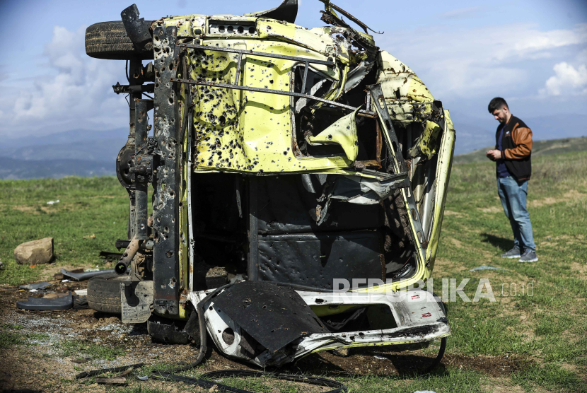 Seorang jurnalis melihat minibus Armenia yang rusak pada Selasa, (3/10/2023), dekat Khankendi, Azerbaijan, juga dikenal sebagai Stepanakert bagi orang Armenia.