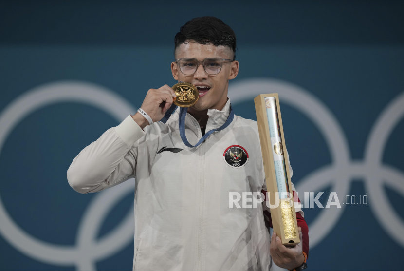 Lifter Indonesia Rizki Juniansyah berpose dengan medali emasnya usai upacara pengalungan medali kelas 73 kg putra Olimpiade Paris 2024 di South Paris Arena, Paris, Prancis, Kamis (8/8/2024). Rizki meraih medali emas setelah berhasil meraih total angkatan 354 kilogram sehingga menduduki peringkat pertama dari 12 lifter yang turut serta dalam nomor tersebut.