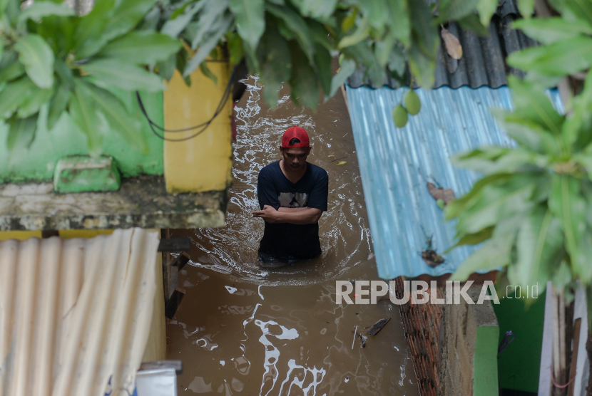 Warga berjalan melintasi banjir yang merendam kawasan Cipinang Melayu, Jakarta Timur, Jumat (19/2). Banjir yang terjadi akibat  luapan Kali Sunter tersebut menggenangi sebanyak lima Rukun tetangga diantaranya RT 01 hingga RT 05 yang bread di RW 04 dengan ketinggian 90 centimeter.