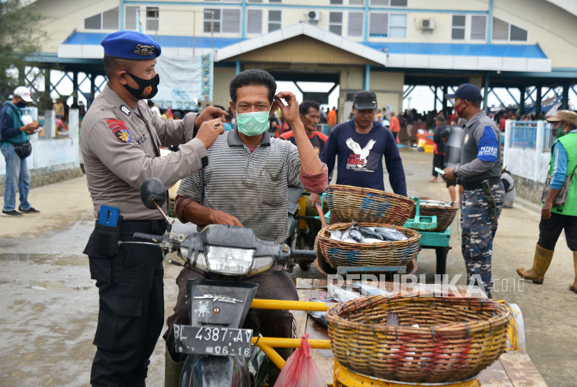 Anggota Polairud bersama prajurit TNI AL membagikan masker kepada nelayan dan pedagang keliling di pusat pelelangkan ikan Pelabuhan Perikanan Samudera, Kotaraja, Banda Aceh, Aceh, Selasa (24/11/2020). Pemerintah terus meningkatan penegakkan disiplin protokol kesehatan kepada masyarakat, salah satunya di pusat keramaian seperti tempat pelelangan ikan untuk menekan peningkatan kasus COVID-19. 